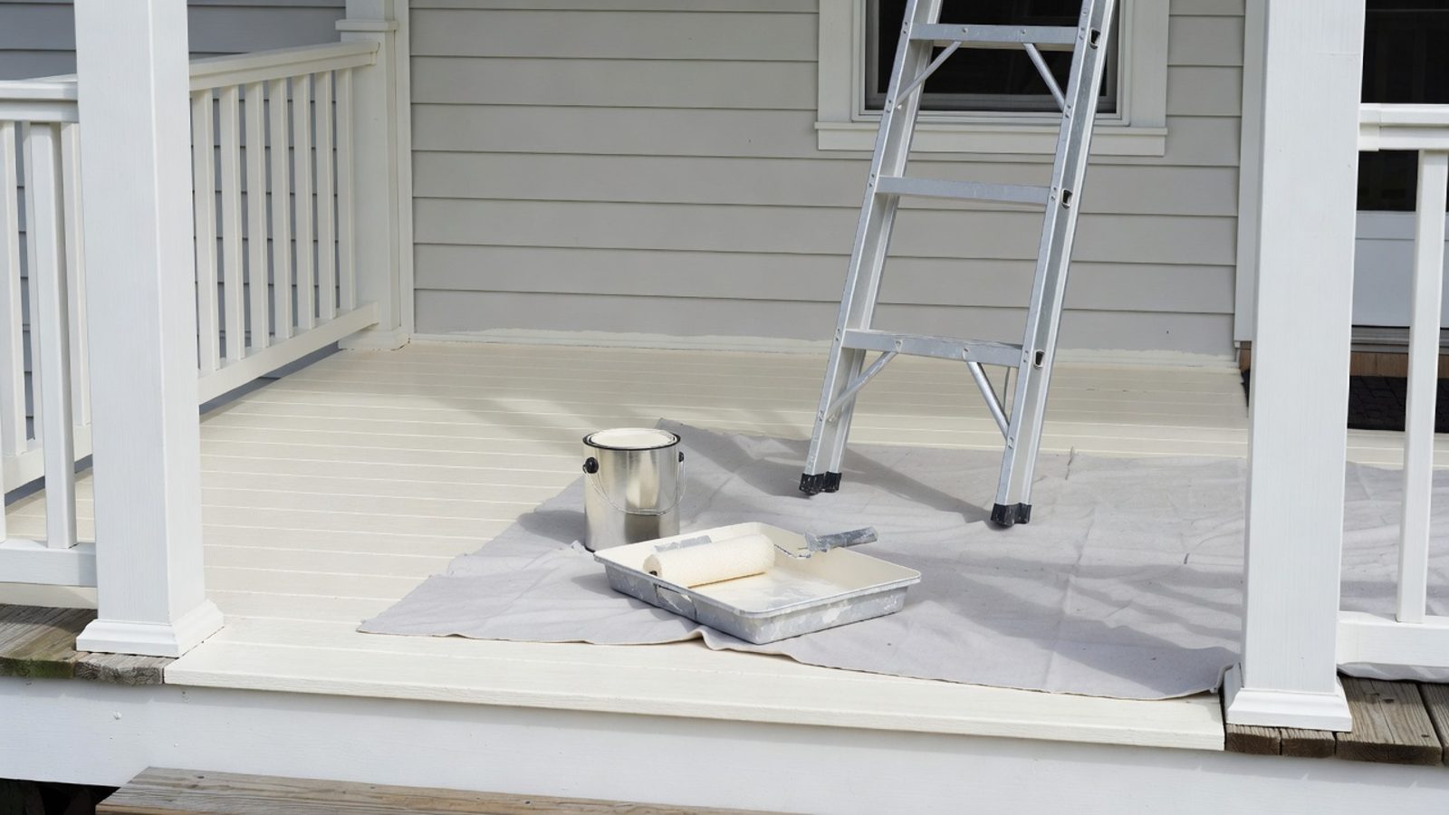 Freshly painted rental porch with a ladder, paint can, and roller tray
